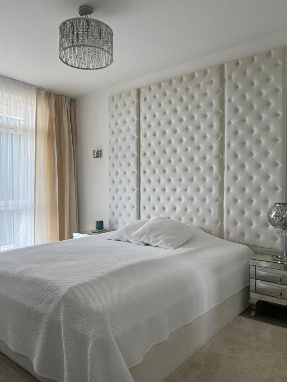 ein Schlafzimmer mit einem weißen Bett mit einem großen Kopfteil in der Unterkunft Oxygen Home in Nyíregyháza