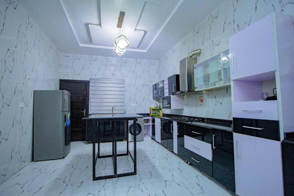 a kitchen with white appliances and a table in it at Treasurablehomes in Maiyegun