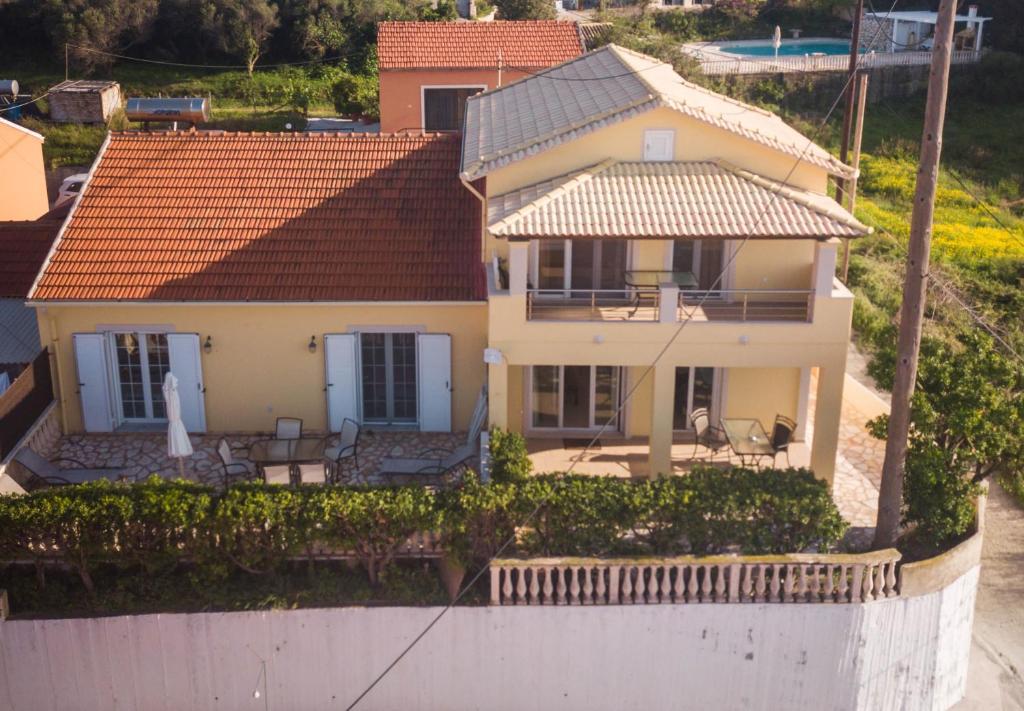 una casa amarilla con techo de baldosa naranja en Antheia Apartments, en Agios Stefanos