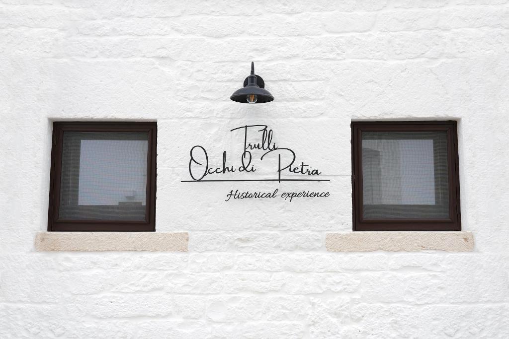 2 fenêtres sur le côté d'un bâtiment blanc dans l'établissement TRULLI OCCHI DI PIETRA HISTORICAL EXPERIENCE, à Alberobello