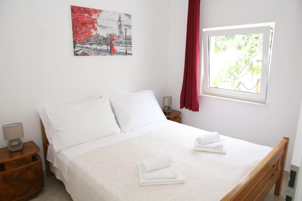 a bedroom with a white bed and a window at Apartments Old Town in Trogir