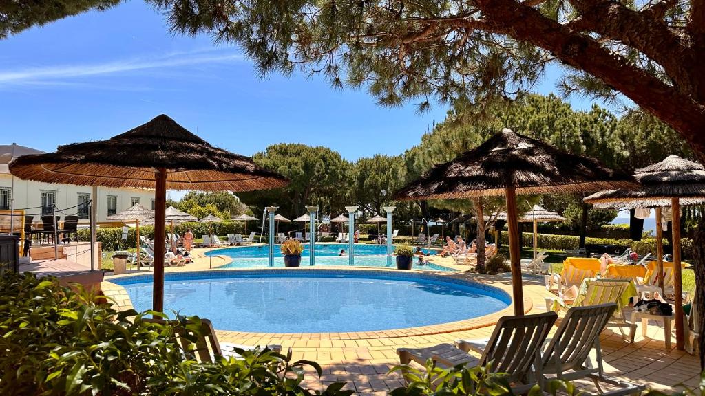 une piscine avec des parasols et des personnes assises autour de celle-ci dans l'établissement Bicos J by Check-in Portugal, à Albufeira