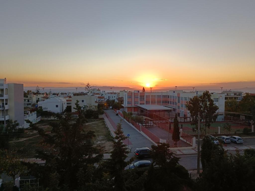 a sunset over a city with cars parked in a parking lot at Cozy Room with Sea View in Athens