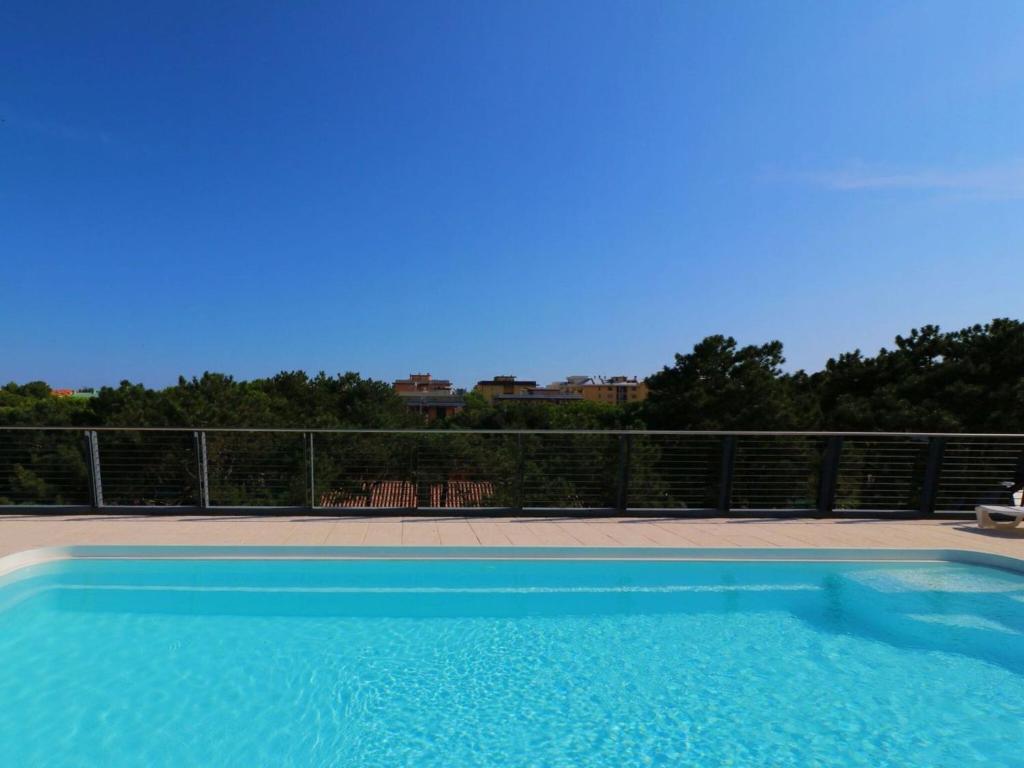 una piscina azul con una valla y árboles en All you need for a perfect holiday - Beahost, en Bibione