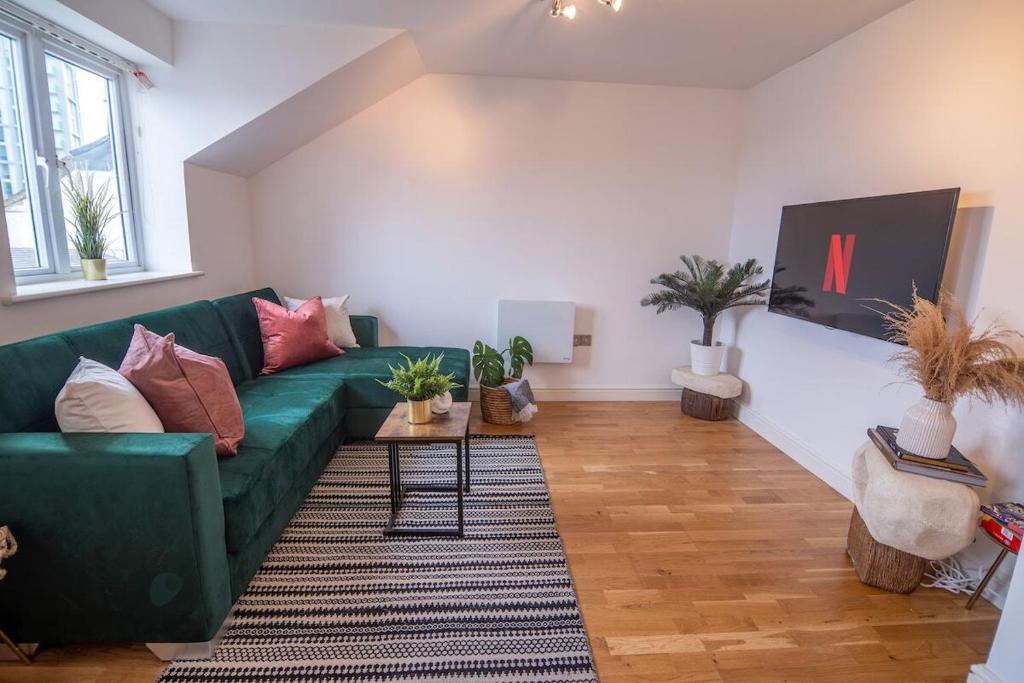 a living room with a green couch and some plants at Cozy Living in Abbey Woods in Abbey Wood