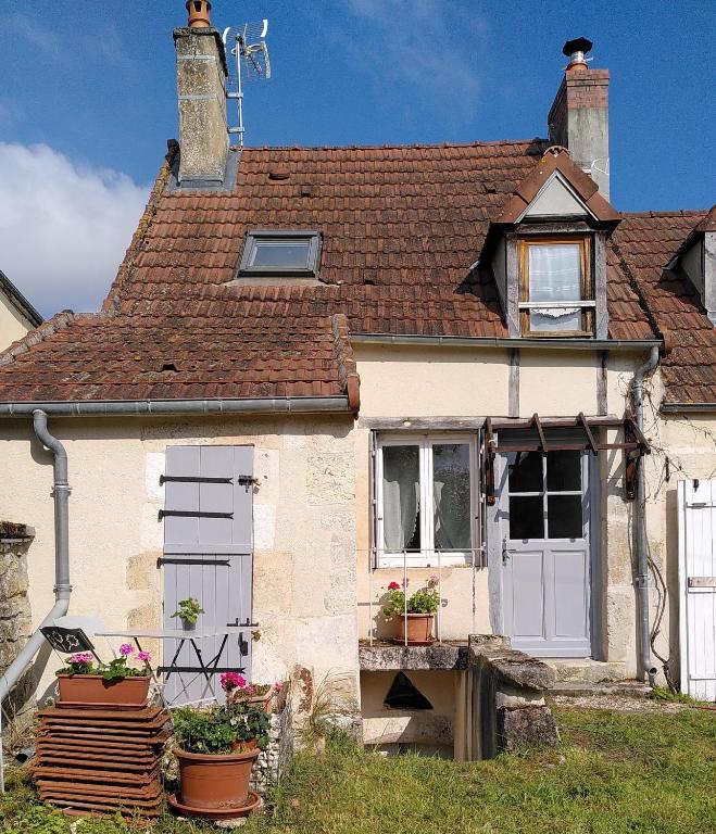 une petite maison blanche avec des plantes en pot devant elle dans l'établissement L'Atelier de Pierre 1-Bed Cottage in Pousseaux, à Pousseaux