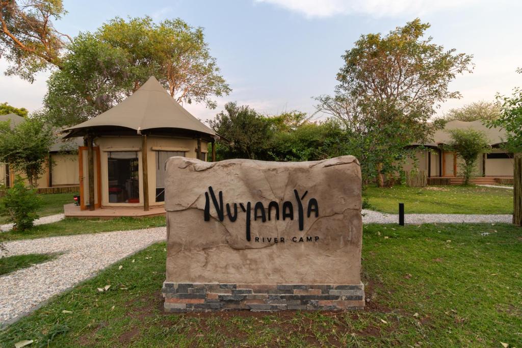 a sign in the grass in front of a building at Nuyanaya River Camp in Chiawa