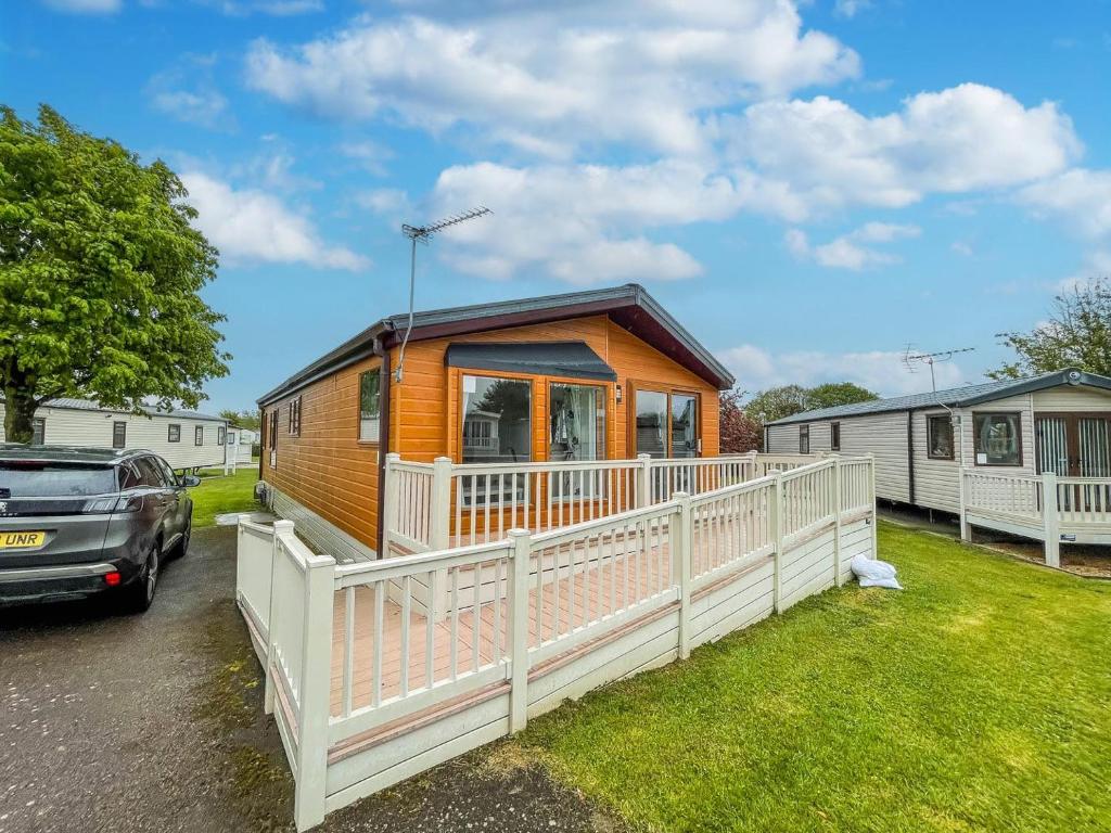 a tiny house in a parking lot with a car at Beautiful 6 Berth Lodge With Disabled Access At Cherry Tree Ref 70829c in Great Yarmouth