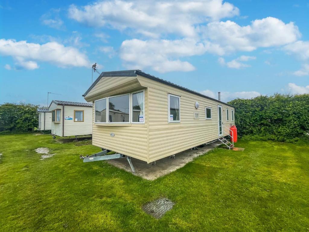 a yellow tiny house in a grass field at Lovely 8 Berth Caravan At California Cliffs Holiday Park In Norfolk Ref 50053c in Great Yarmouth