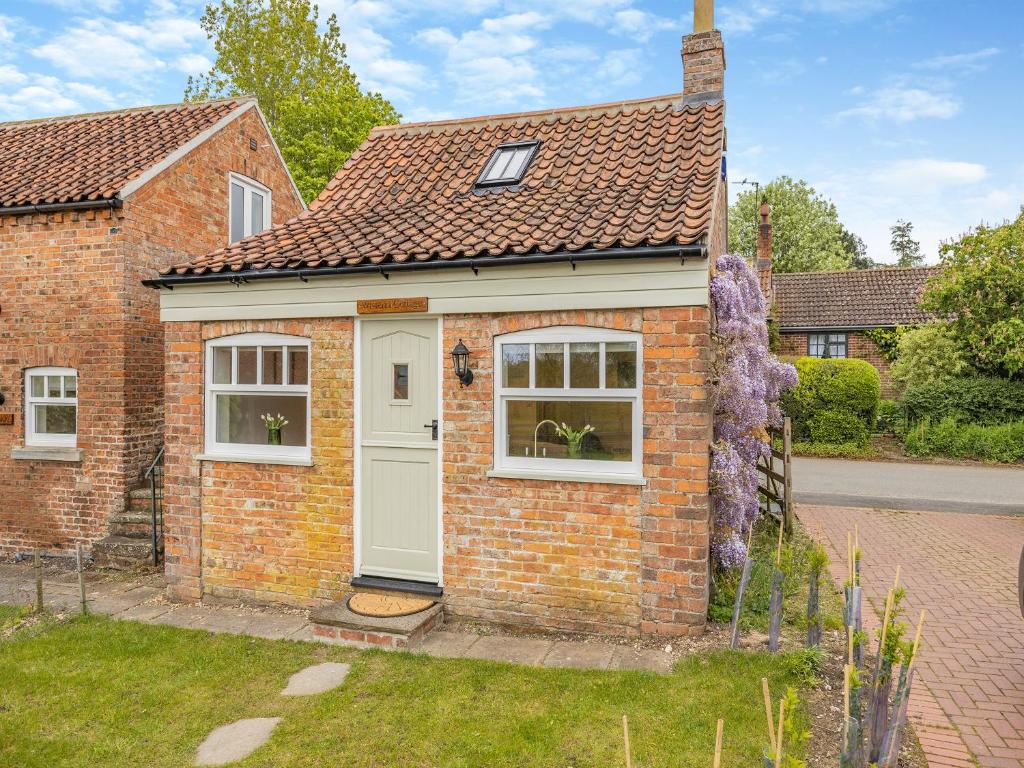 una casa in mattoni con porta bianca e finestre di Wisteria Cottage - Uk46478 a Hemingby