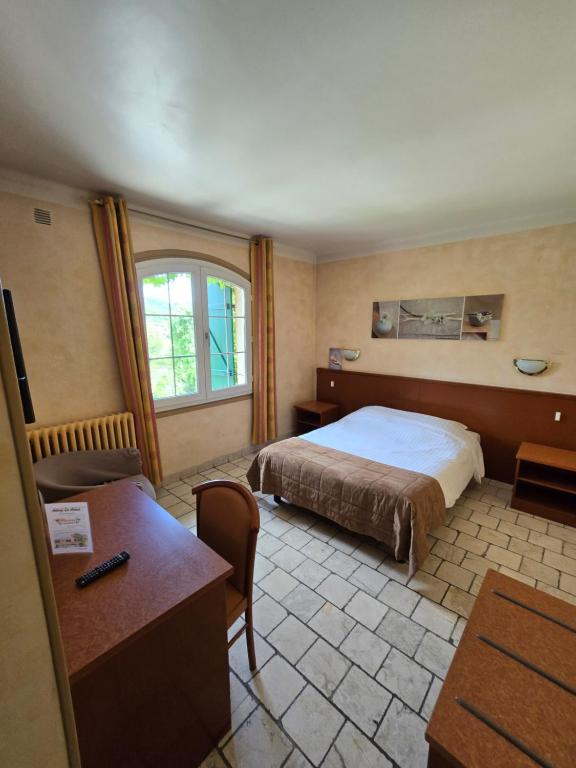 グラースにあるオーベルジュ レ アロームのベッドとデスクが備わるホテルルームです。