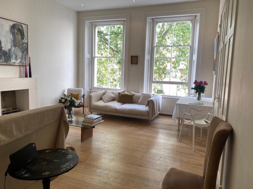 - un salon avec un canapé et 2 fenêtres dans l'établissement Beautiful Hyde Park Flat, à Londres