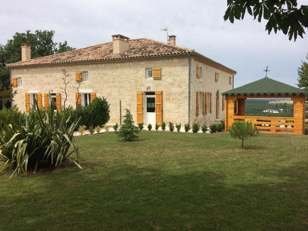 une vieille maison en pierre avec un kiosque dans une cour dans l'établissement Gîte de Couet, à Caumont