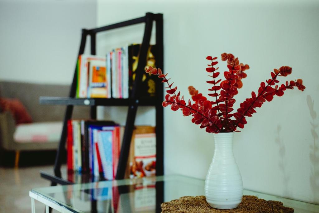 a white vase with red flowers on a glass table at Sumanas Homestay Ijen in Banyuwangi