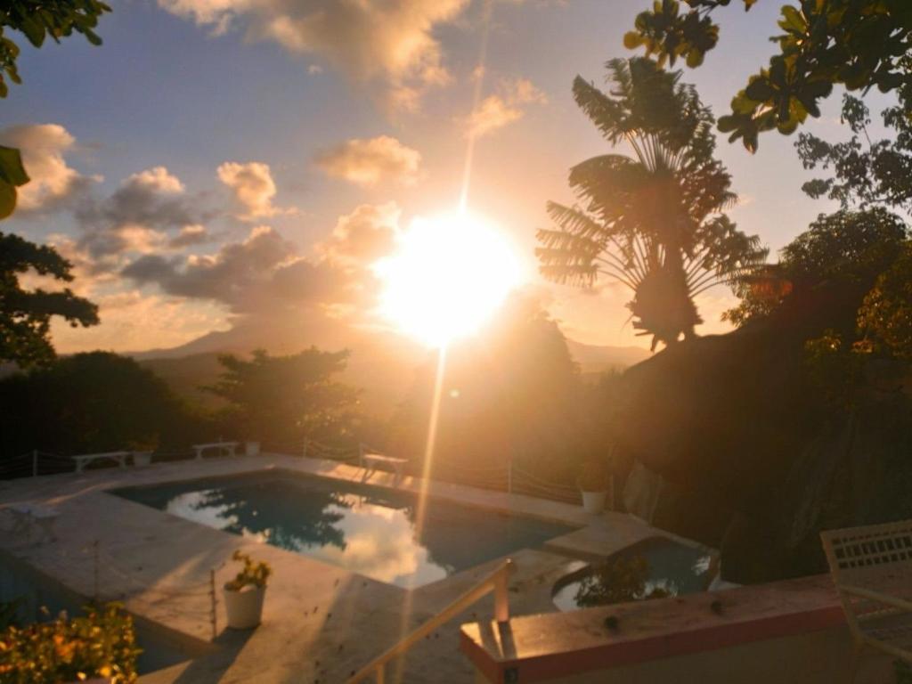 a sunset over a swimming pool with the sun setting at Kikis Beach House in Fajardo