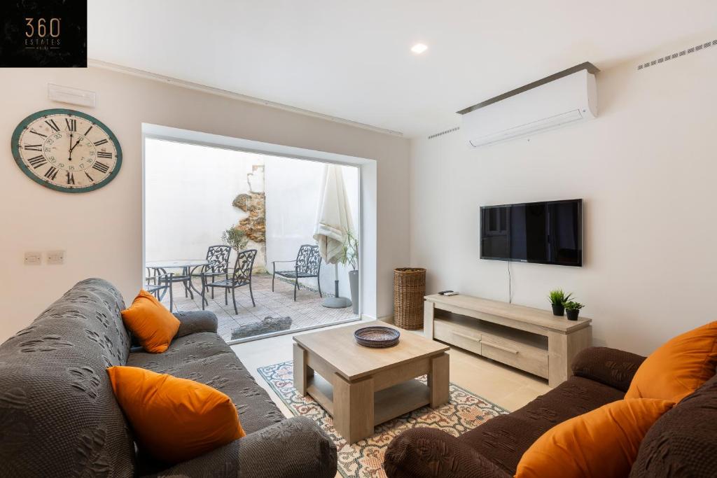 sala de estar con sofá y reloj en la pared en 4BR Home in Prime Location Just Off the Promenade by 360 Estates, en Sliema