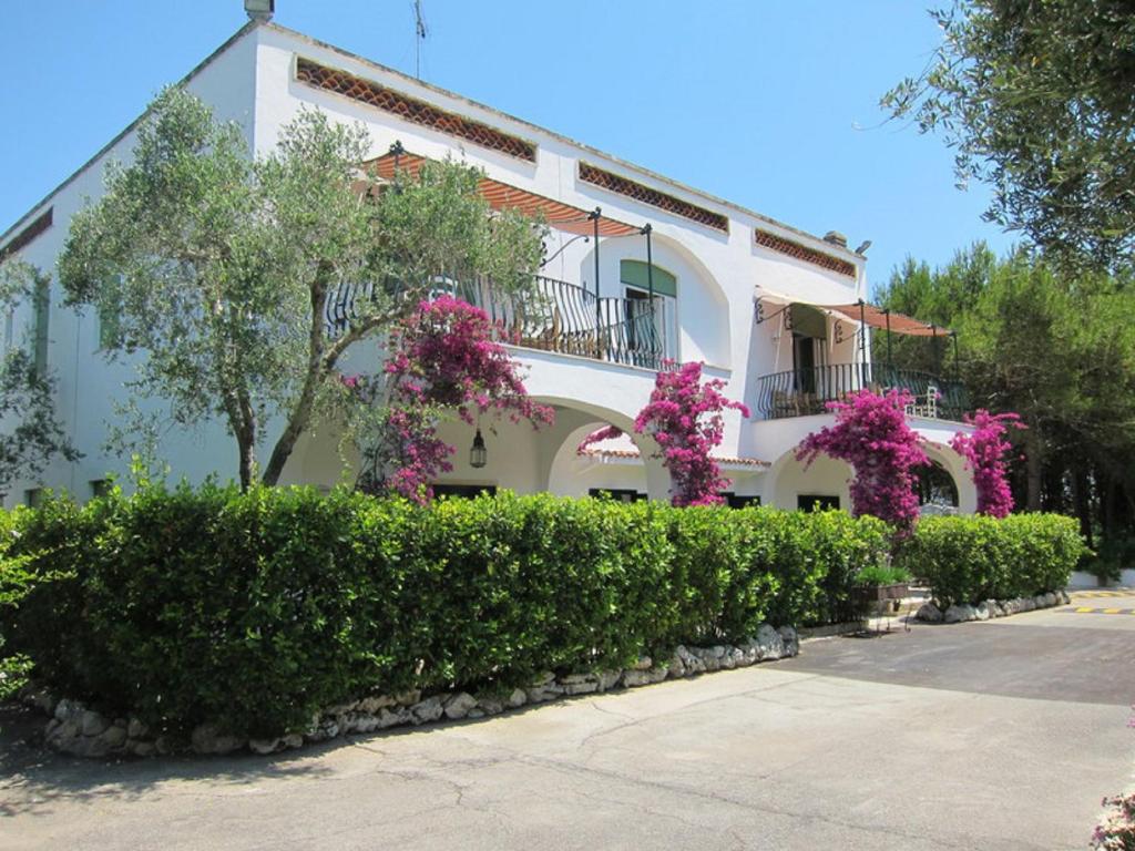 Biały budynek z różowymi kwiatami przed nim w obiekcie Tenuta Belvedere w mieście Otranto