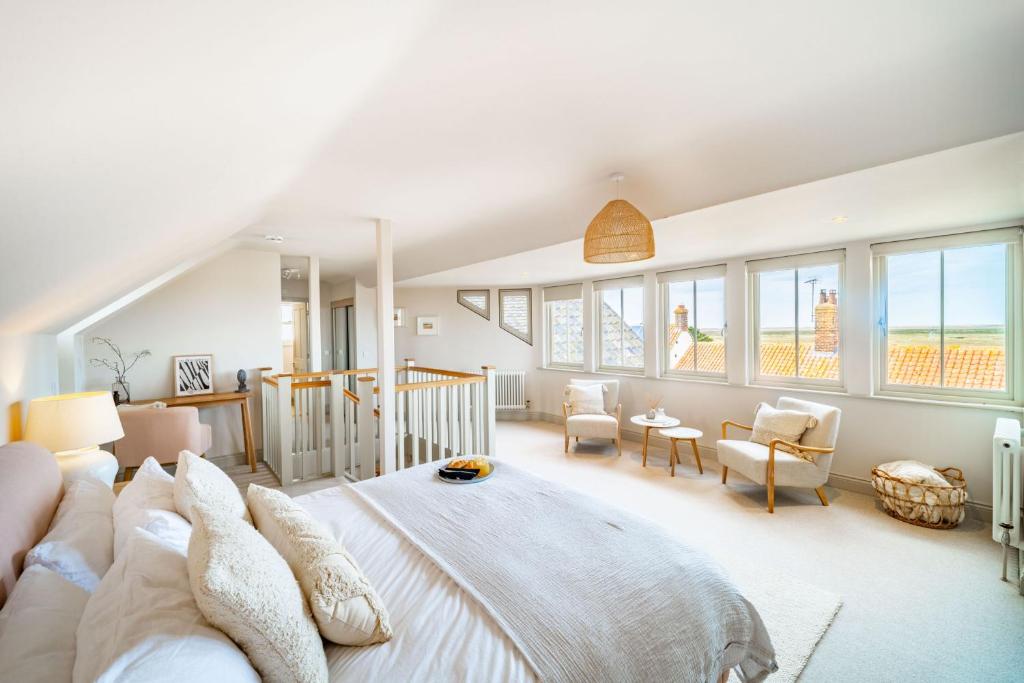 1 dormitorio con 1 cama grande en una habitación con ventanas en White Horses - Sleeps 2 by Big Skies Cottages, en Blakeney