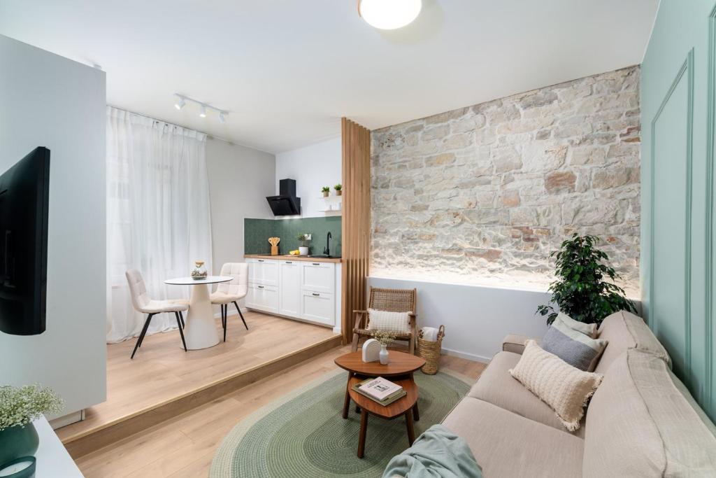 a living room with a couch and a brick wall at New Premium Apartment Rivetta in Poreč