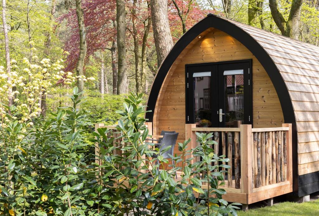 een kleine hut in het bos met een houten deur bij Boslodges Veluwe in Nunspeet