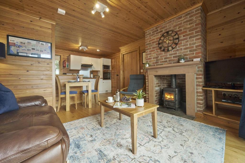 een woonkamer met een bank en een open haard bij Chiffchaff Lodge with Hot tub in Carlisle