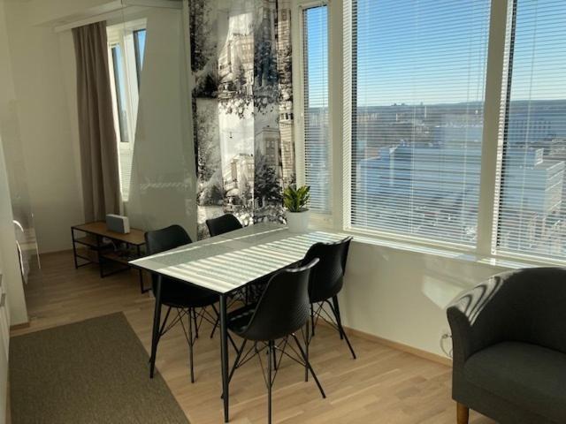 a dining room with a table and chairs and a large window at Topaasi in Tampere
