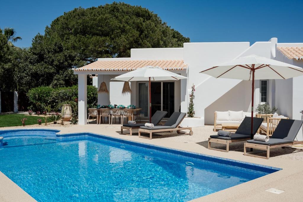 a villa with a swimming pool and two chairs and umbrellas at The Carobs Villas in Carvoeiro