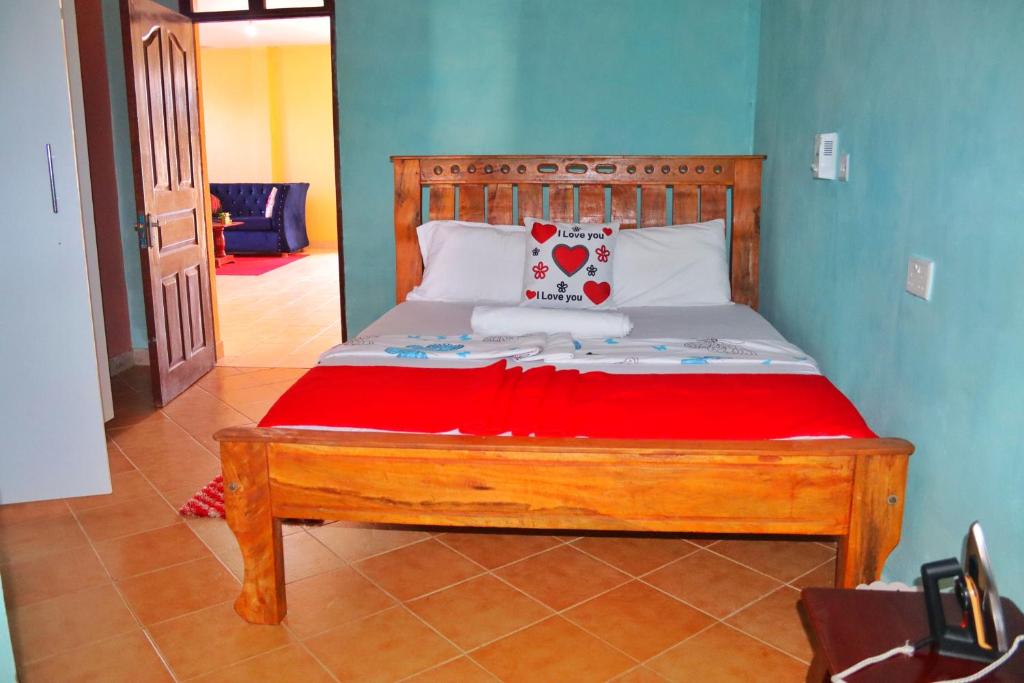 1 dormitorio con cama de madera y manta roja en Shanzu Budget Traveler Homestay, en Mombasa