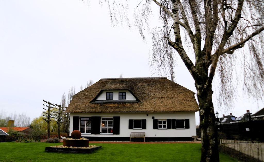 a white house with a brown roof and a tree at Mimosa bed & breakfast in IJsselmuiden in IJsselmuiden
