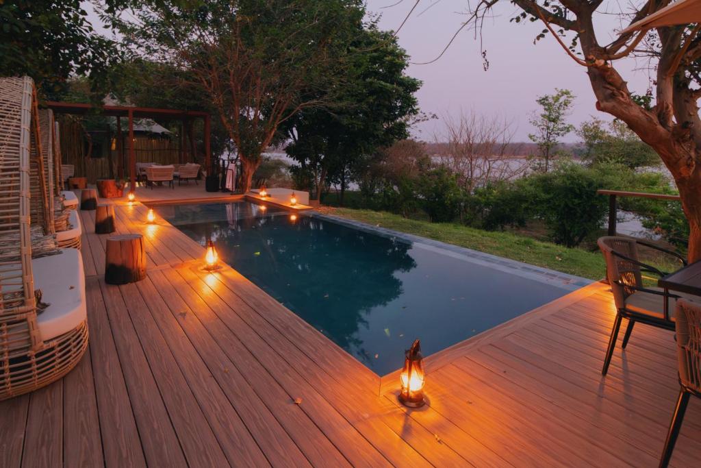 - une piscine éclairée sur une terrasse en bois dans l'établissement Nuyanaya River Camp, à Chiawa