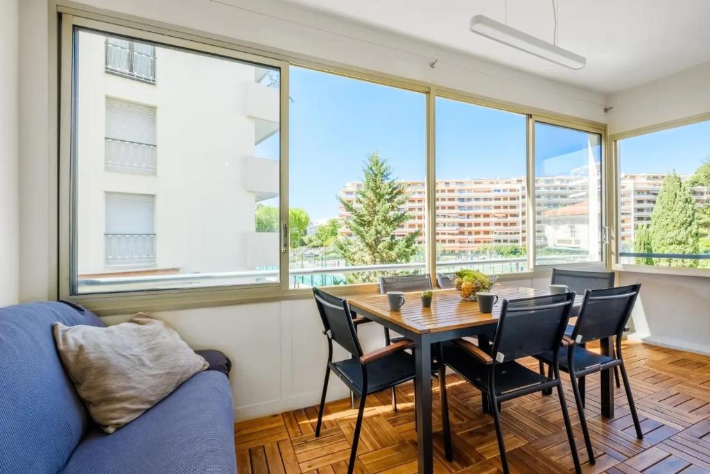 une salle à manger avec une table, des chaises et des fenêtres dans l'établissement Croisette Beach Apartment 2 Bedroom and Terrace, à Cannes
