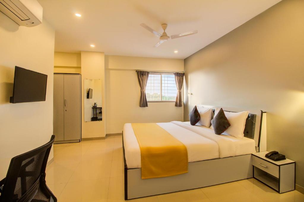 1 dormitorio con 1 cama grande y TV en Housemate Hotel, en Pune