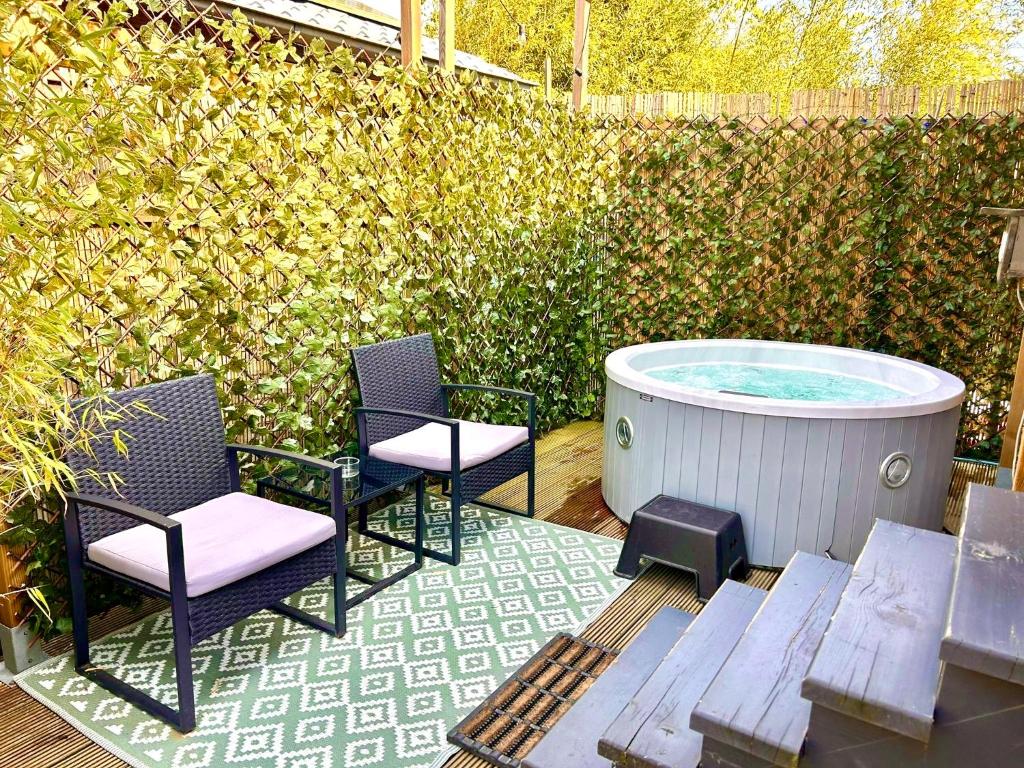 a patio with two chairs and a hot tub at Tiny house with garden and jacuzzi near Amsterdam in Vijfhuizen