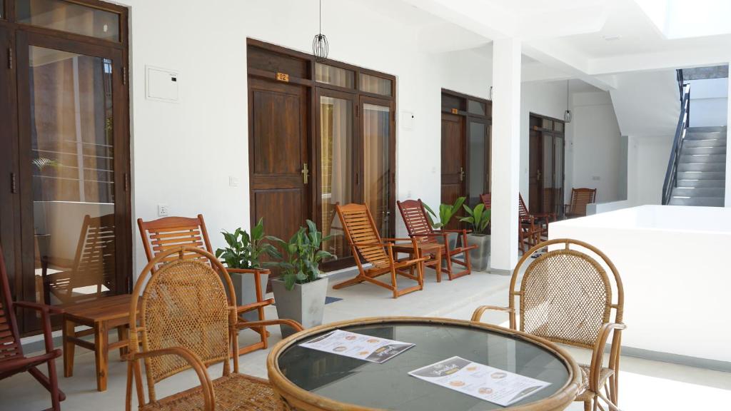 um quarto com cadeiras e uma mesa de vidro em The White Pillow em Arugam Bay
