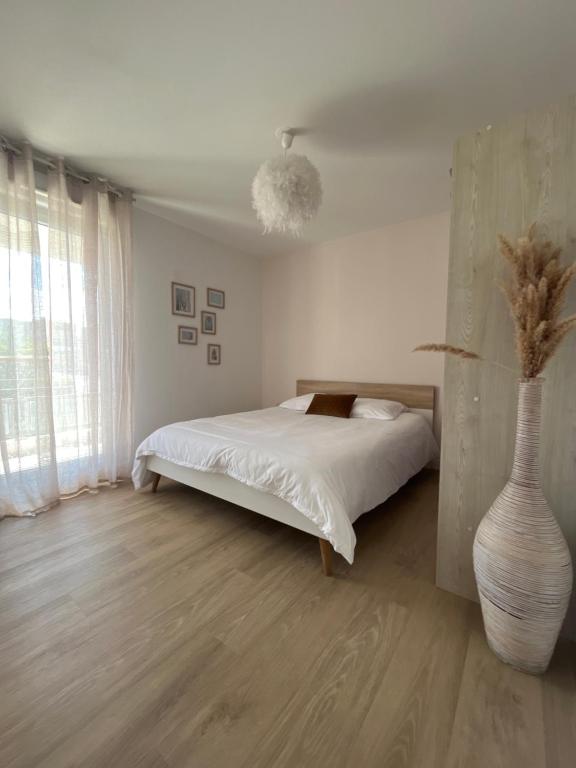 a white bedroom with a bed and a vase at Appartement 2 chambres dans résidence avec piscine et parking in La Ciotat