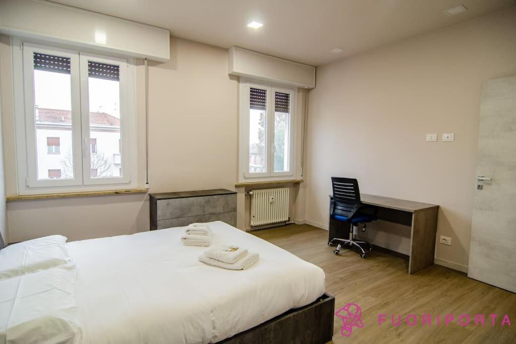 een slaapkamer met een bed, een bureau en ramen bij Residenza Gramsci 13 in Parma