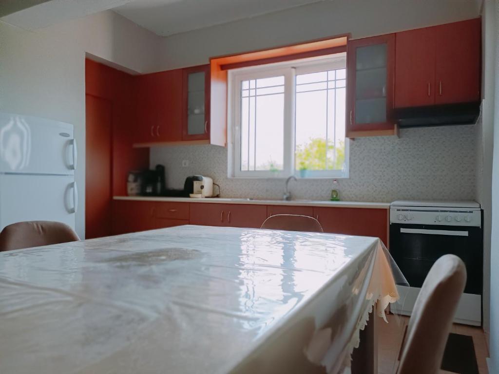 een keuken met rode kasten en een tafel met stoelen bij Luxurious Apartment Katakolo Beach in Katakolon