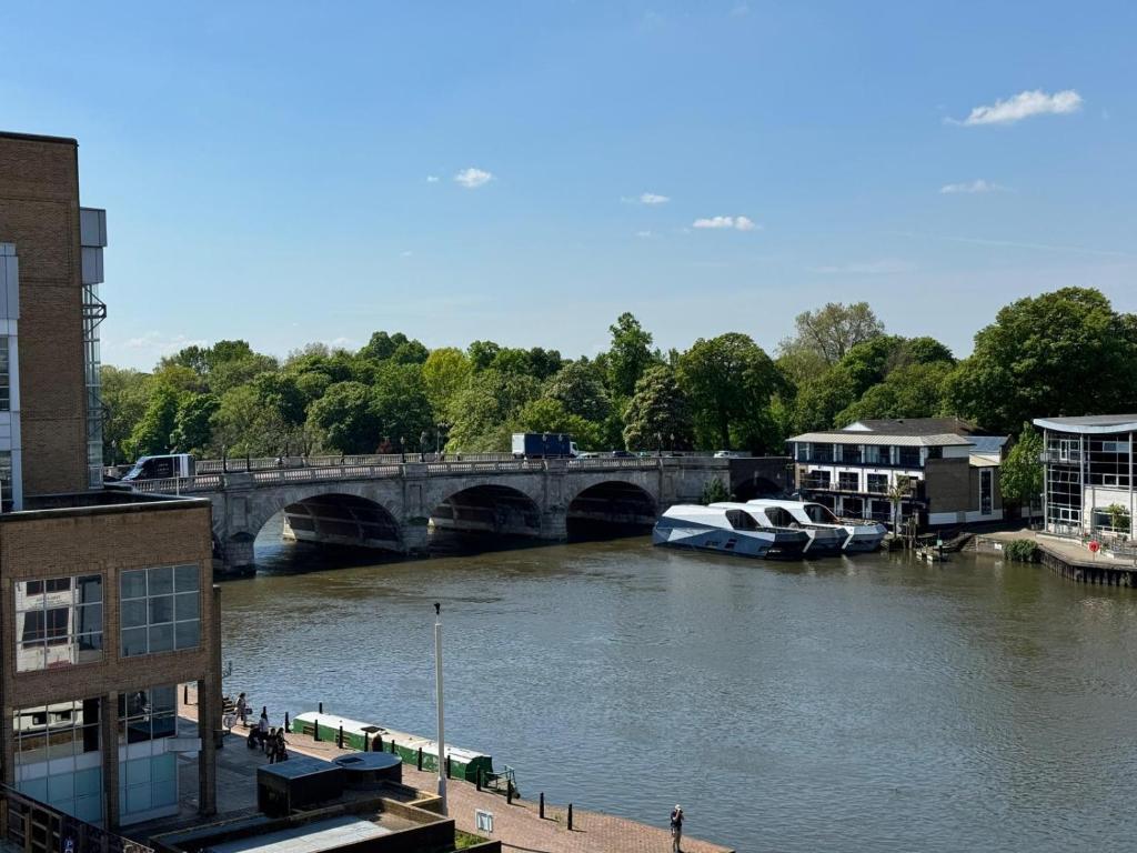 a boat is docked on a river with a bridge at Entire Kingston Two bedroom Apartment Town centre & River view, 32 minutes to London Waterloo Station in London