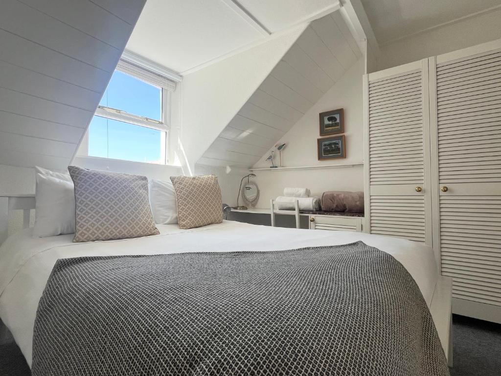 um quarto com uma grande cama branca e uma janela em Charming Two Bed house in Central Penzance em Penzance