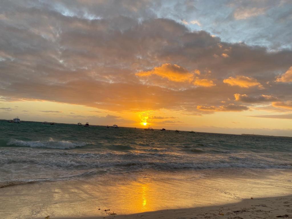 una puesta de sol en la playa con el océano en Hostal Las Rosas de Punta Cana, en Punta Cana