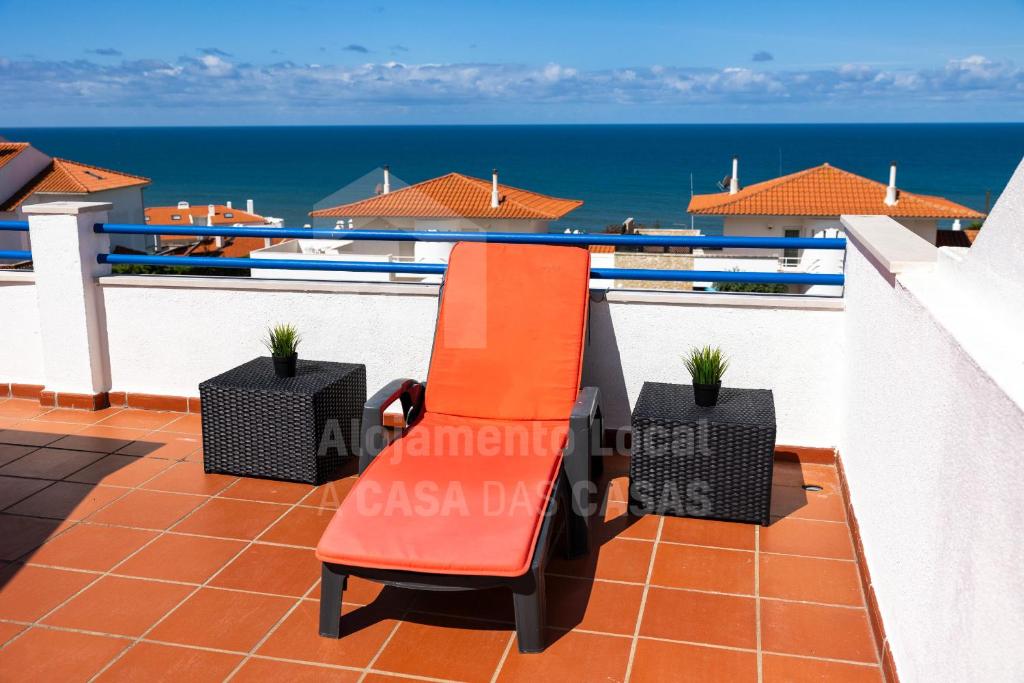 a red bench on a balcony with the ocean at Casa do Sol by AcasaDasCasas in Ericeira