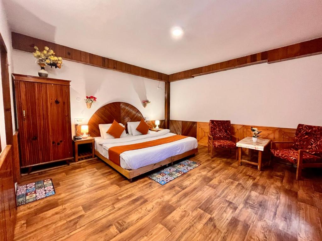 a hotel room with a bed and two chairs at Ganga Cottage !! 1,2,3 bedrooms cottage available near mall road manali in Manāli