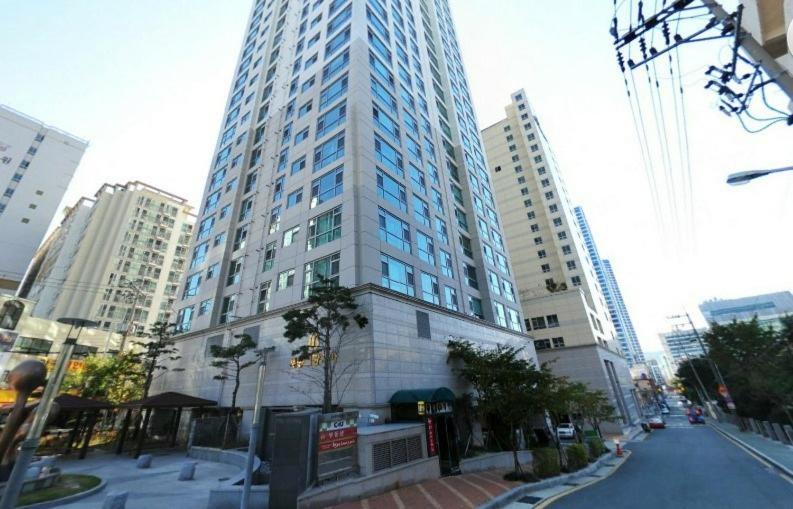 um edifício alto numa rua da cidade com edifícios altos em Big Party Room House em Busan
