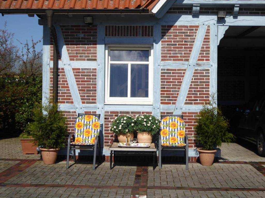 Süderschweiburg的住宿－Casa Carina Ferienhaus, Oberwohnung mit kleinem Sonnenbalkon und Terrasse，一座房子,配有两把椅子和一张带鲜花的桌子