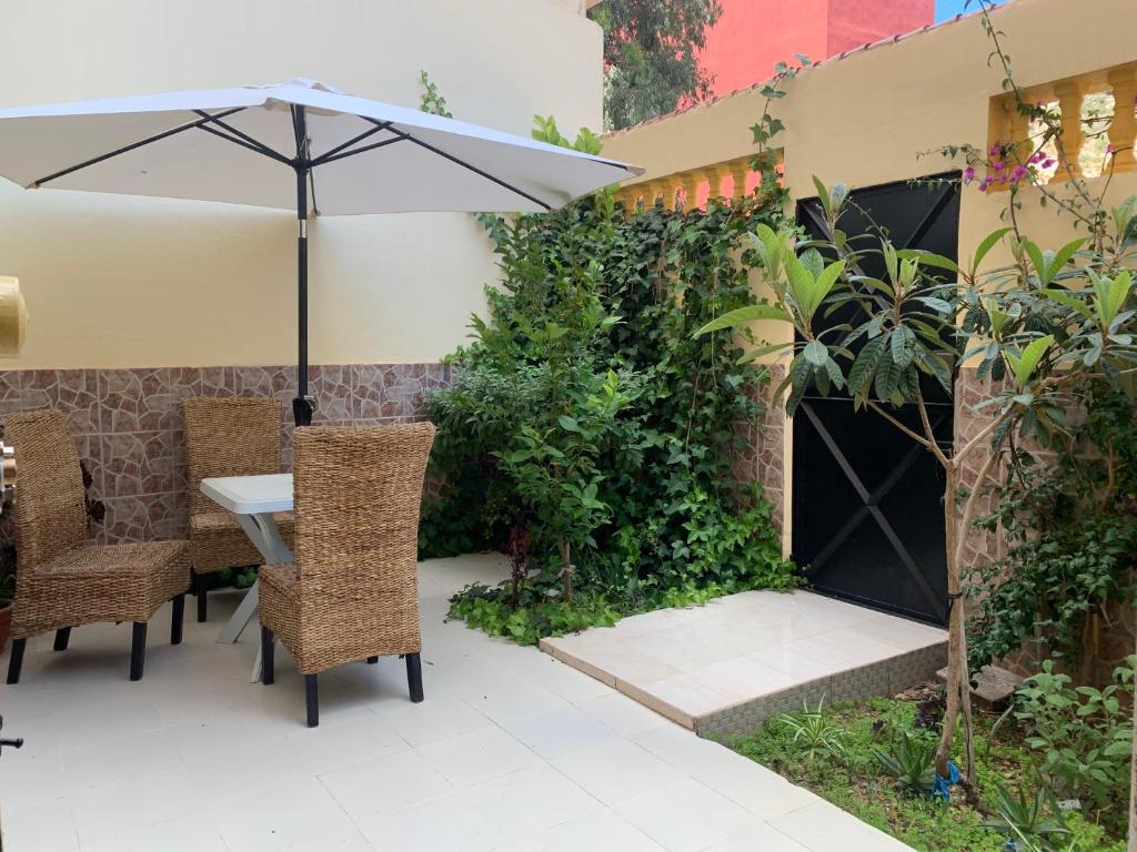 een patio met een tafel en stoelen en een parasol bij Al houceima in Al Hoceïma