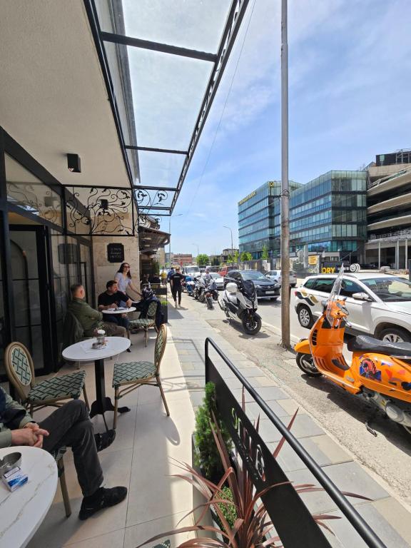 a balcony with people sitting at tables and cars on a street at In Town Boutique HOTEL in Pristina