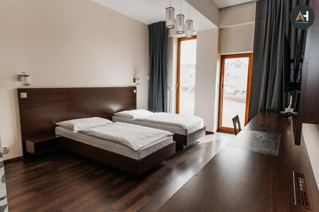twee bedden in een slaapkamer met houten vloeren en een raam bij Charlotte City Center Apartment in Košice