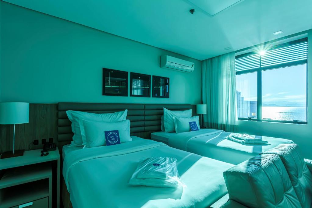 a blue room with two beds and a window at Blue Tree Premium Florianópolis in Florianópolis