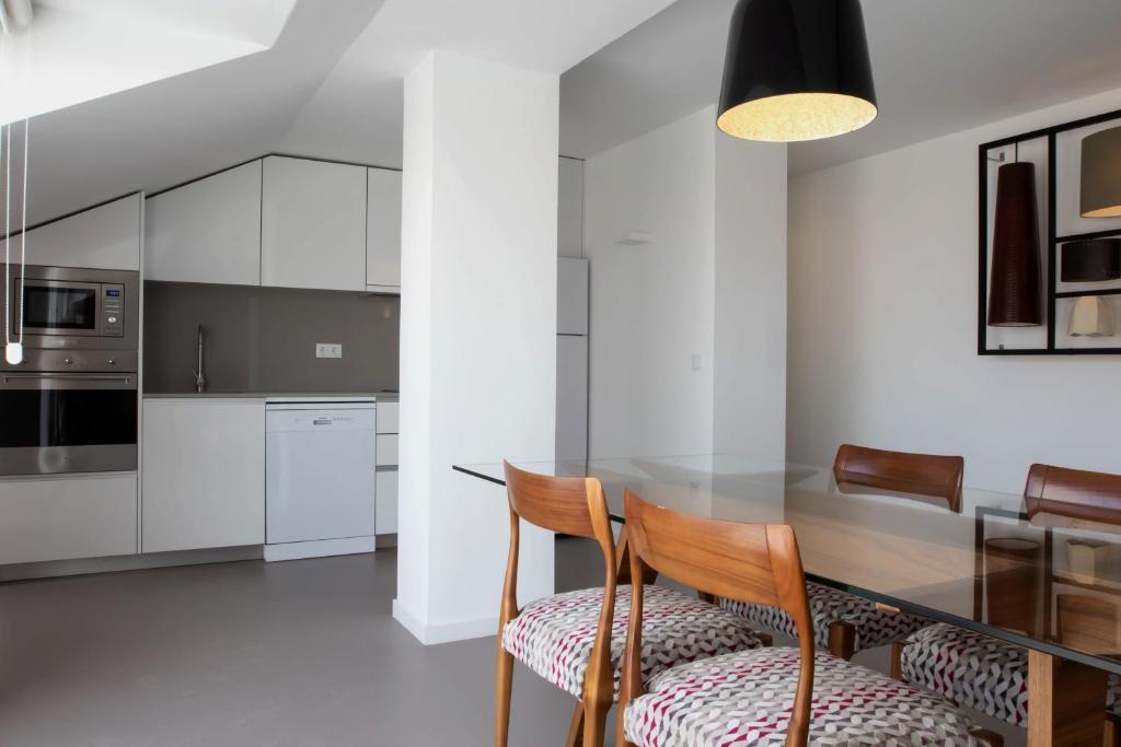 A compact fitted kitchen opening onto a glass dining area.
