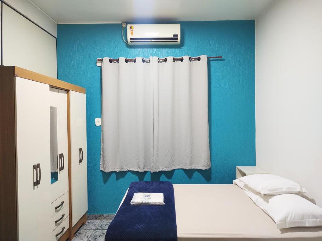 Habitación azul con cama y cortina en Apartamento aconchegante em Cacoal4, en Cacoal